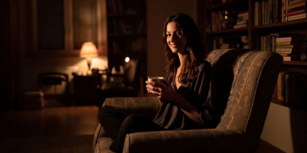 Mamma single seduta sul divano di casa la sera con una tazza in mano